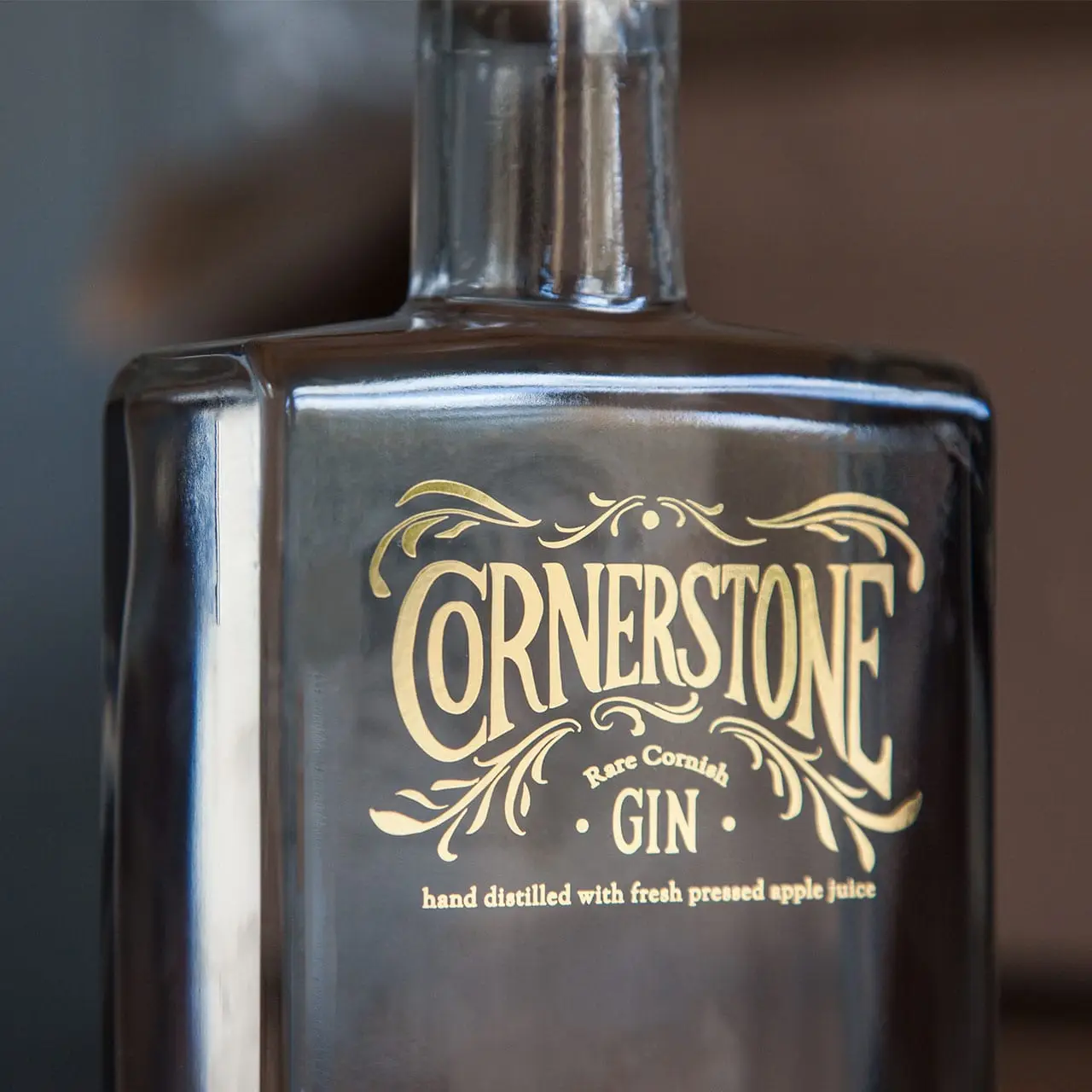 A close-up photograph of the Cornerstone rare Cornish gin bottle gold label design and branding