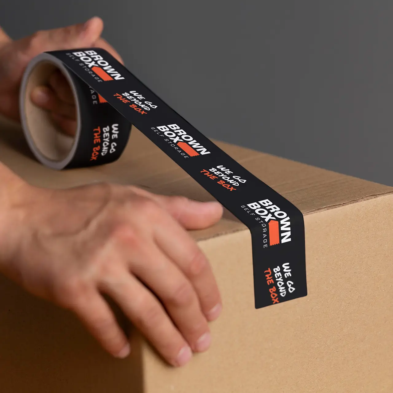 Brown box storage branded tape being applied to a cardboard box.