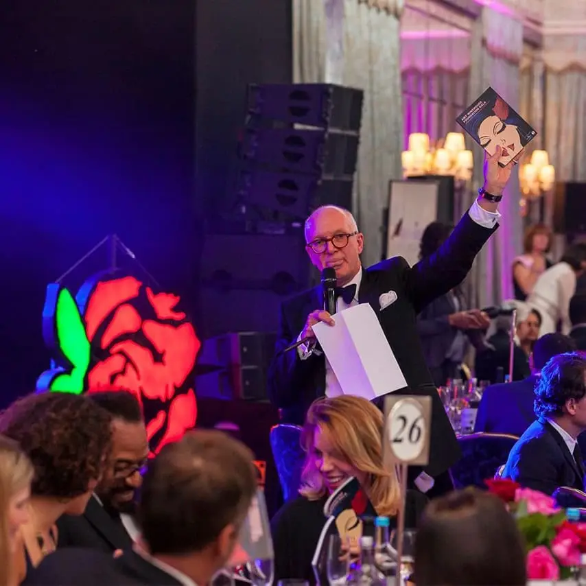 An image of a presenter holding up the brochure at the Amy Winehouse Foundation Gala