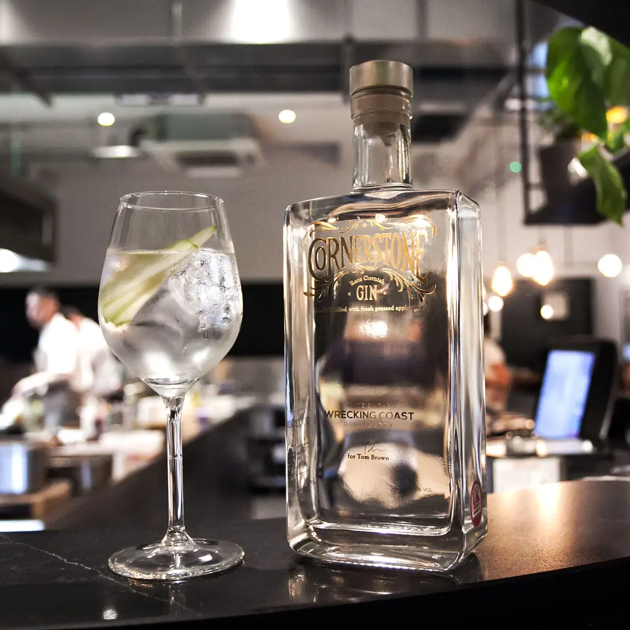 A photograph of the Cornerstone gin bottle with a gin glass on the bar-top at Tom Brown's restaurant Cornerstone Hackney Wick in London