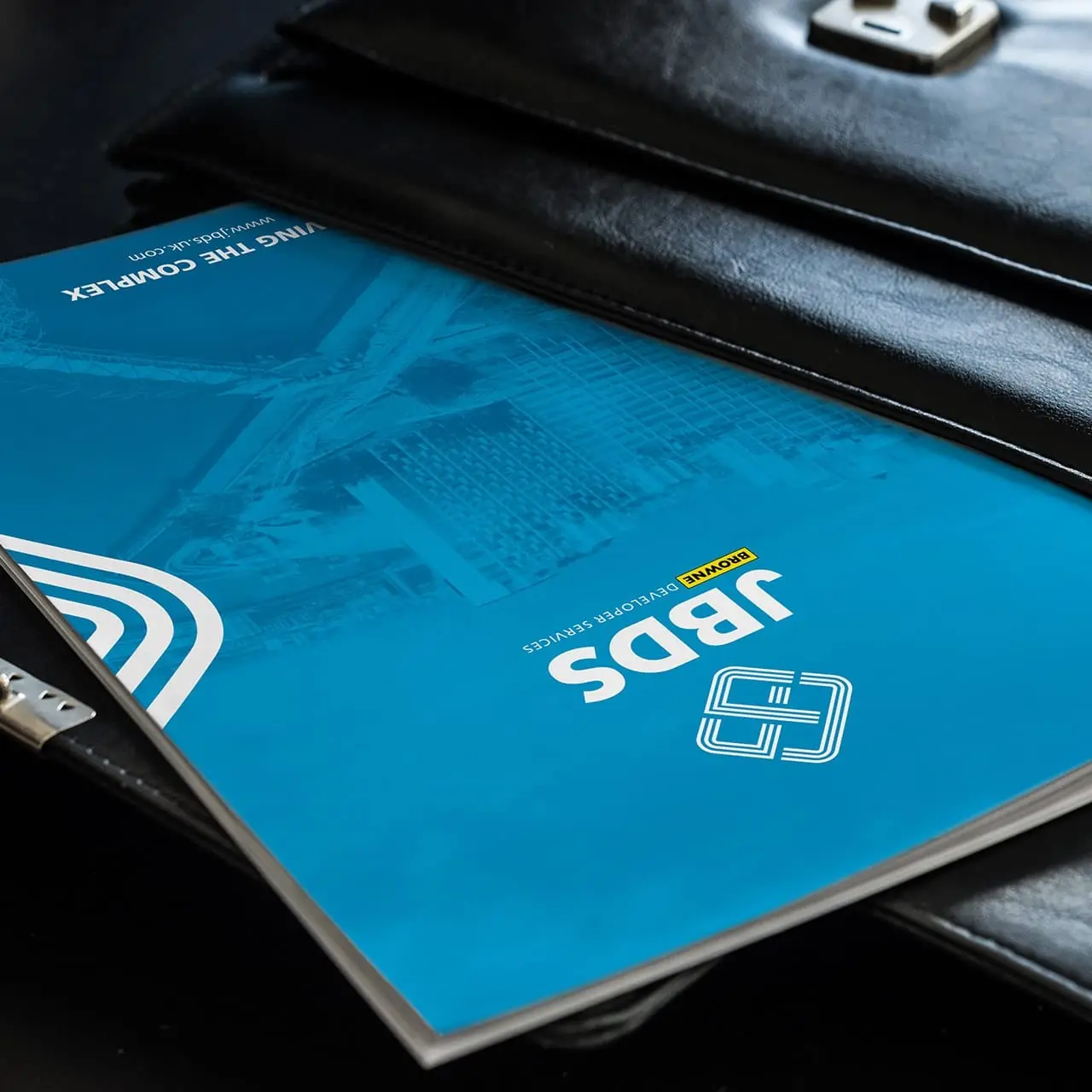 A branded construction company brochure sliding out of the inside of a leather bag